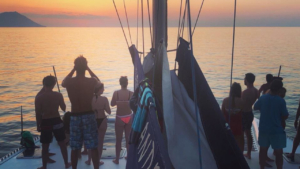 Relax on deck as the sky turns gold over calm Aegean waters